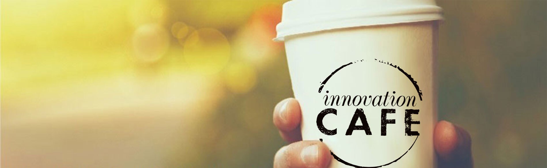 A takeaway coffee cup printed with the logo of Swanson Reed's innovationCAFE
